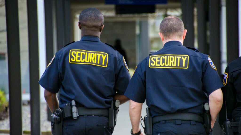 Two security guards are walking down the street.