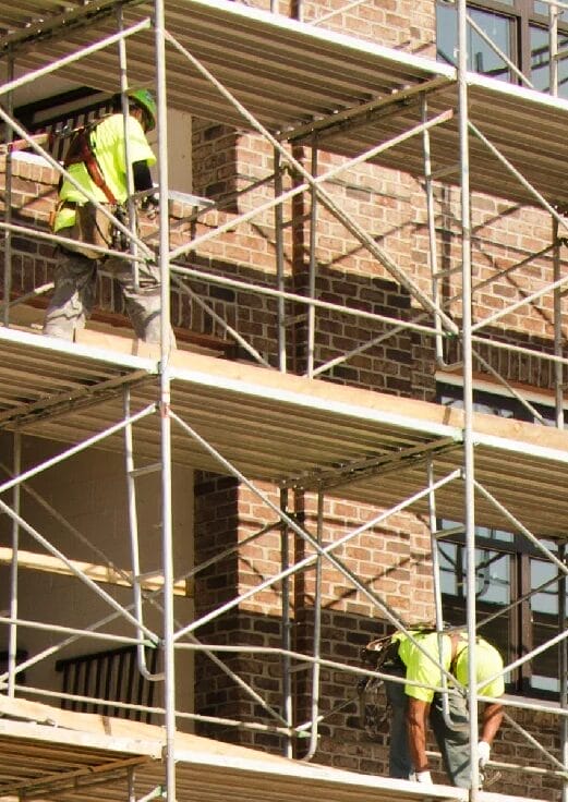 Two men are working on scaffolding in a building.