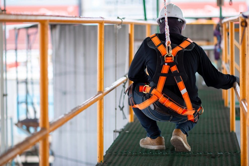 A man in safety harness and helmet on a bridge.