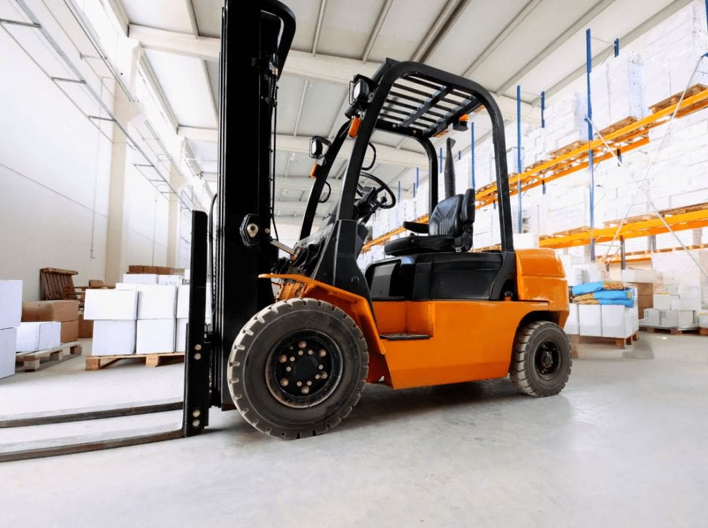 A forklift is parked in the middle of a warehouse.