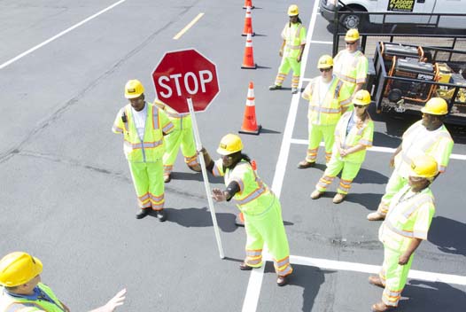 A group of construction workers holding up a stop sign.