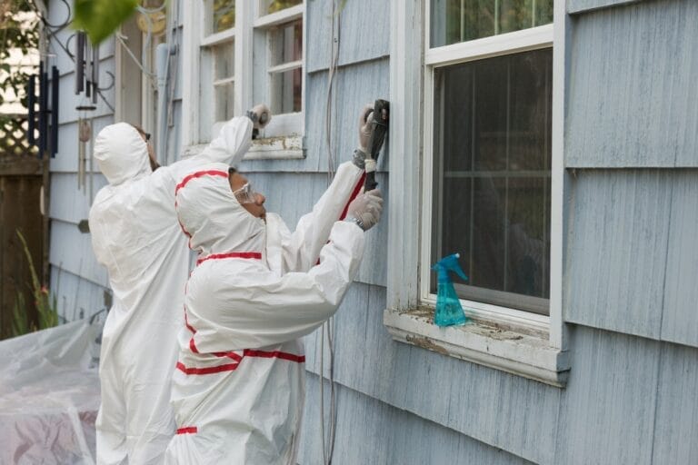 Workers in hazmat suits cleaning window.